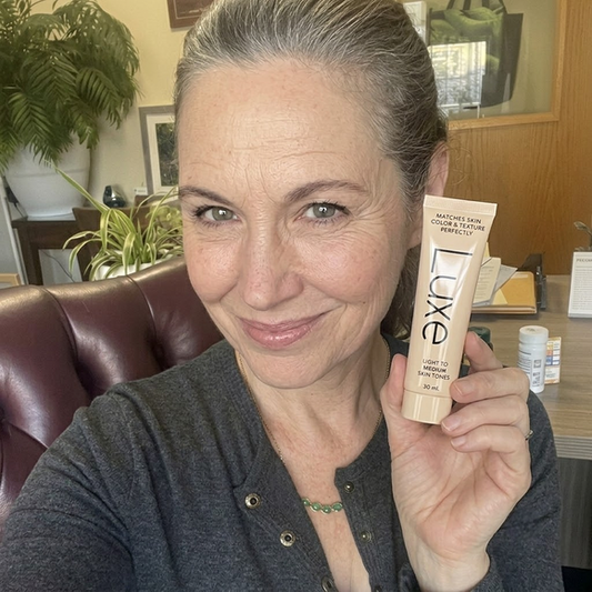 Woman holding Luxe Color Changing Foundation tube